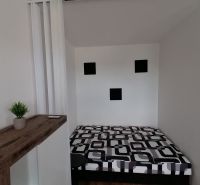 Bed and decoration in a one-room apartment with a wooden decor floor.