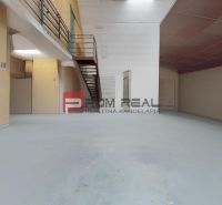 A large warehouse interior with a metal floor, staircase, and storage space.