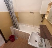 A bathroom in a 3-room apartment with a bathtub and a floor with a wooden decor.