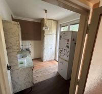 The kitchen of a three-room apartment with a wooden-patterned floor and a patterned kitchen unit.