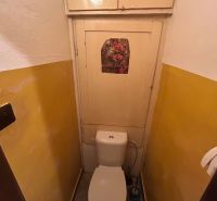 A toilet with a floral picture and a yellow wall in a 3-room apartment.
