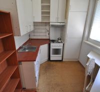 A kitchen in a three-room apartment, with a stove, cabinets, and a floor with a wood decor.