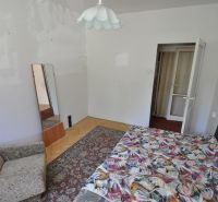 Bedroom in a 3-room apartment with a bed, chair, mirror, and floor with a wooden decor.