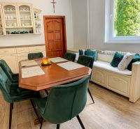A family house with a dining table, green chairs, and a wooden decor floor.
