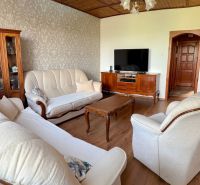 Living room in a family house with wood-patterned flooring and cream furniture.