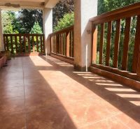 A balcony of a family house in Sady nad Torysou with brick paving and wooden railing.