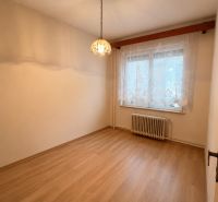 A room in a family house with a wooden decor floor, curtains, a radiator, and a chandelier.