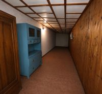 A hallway in a family house with wooden paneling and a blue cabinet on the wall.