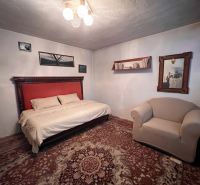 Bedroom in a family house with a large bed, armchair, paintings, and decorations on the wall.