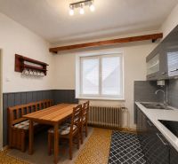 A kitchen in a family house with a dining table and wooden chairs.