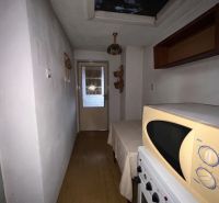 A narrow kitchen with a microwave and a wooden decor floor in a family house.