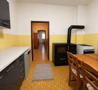 A kitchen in a family house with a stove, a wooden table, and yellow tiles.