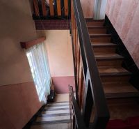 A staircase in a family house with detailed wallpaper and a curtain by the window.