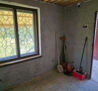 The interior of a cabin with a window, tools, and a bucket on the floor with wooden decor.