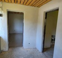 The interior of a cabin with bare walls, a concrete floor, and a wooden ceiling.