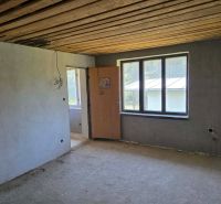 The interior of the cabin with a concrete floor, empty walls, horizontal wooden ceiling.