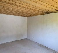 The interior of the cabin with a wooden ceiling and an unfinished floor.
