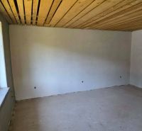 A room in a cabin with a rough floor and a wooden ceiling.