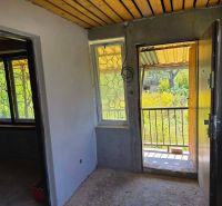 A cottage with a wooden ceiling, a view from the front door, and a window grille.
