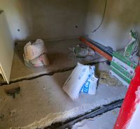 A cottage under reconstruction with materials on a concrete floor, ready for construction work.
