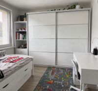 Children's room in a three-room apartment with a desk, bed, and wardrobe, floor with wooden decor.