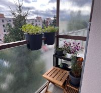 A balcony with flowers and a wooden table in a 3-room apartment on Papiernícka Street in Ružomberok.