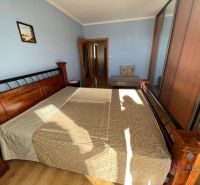 Bedroom in a 3-room apartment with a wooden decor floor and a large bed.