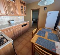 A kitchen in a 3-room apartment with wooden cabinets and ceramic flooring.