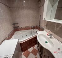 A bathroom with a corner bathtub and a sink in a 3-room apartment, tiles with a pattern.