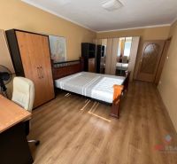 Bedroom with wood-patterned flooring in a 3-room apartment, with a bed and a desk.