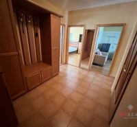 A hallway in a 3-room apartment with ceramic tiles and wooden furniture.