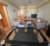 Living room in a three-room apartment with sofas and a glass table, floor with wood decor.