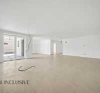 A spacious room with a wood-patterned floor, large window, and white walls.