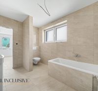 A bathroom in a family house with a bathtub, toilet, and tiled walls.
