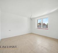 An empty room in a family house with a large window and a wooden-patterned floor.