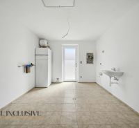 A white room in a family house with a sink and a boiler on the wall.