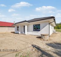 A family house in Tomášikovo with white plaster and a sloping black roof.