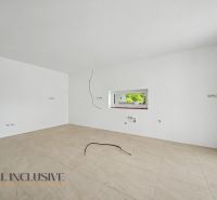 Empty room with white walls, a window, and a wooden-patterned floor in a family house.