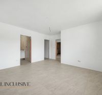 A spacious room with white walls and a wooden decor floor in a family house.