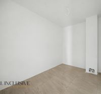 An empty room in a family house with white walls and a wooden-patterned floor.