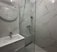 A bathroom in a 2-room apartment with modern white tiles and a shower corner.