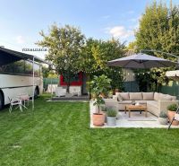 A yard with a bus, a couch, and a parasol by a cottage in Bánovce nad Bebravou.
