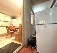 A cottage kitchen with a white refrigerator, wooden seating, and a dining table.