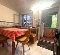 The interior of the cottage with a checkered tablecloth on the table and chairs with backrests.