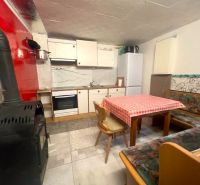 A kitchen in a cottage with appliances, a fireplace, a dining table, and a seating area.