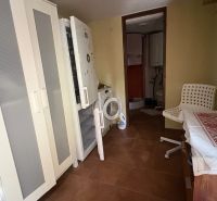 Kitchen area in the Cottage with a refrigerator, a cupboard, and a white armchair.