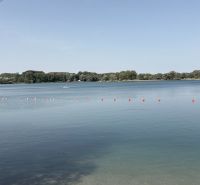 A lake with buoys surrounded by greenery in Bodíky.