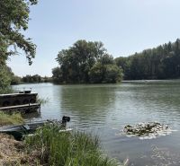 The river near the cottage in Bodíky, with a boathouse and overgrown banks.