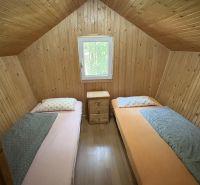 A wooden interior of a cabin with two beds and a window.