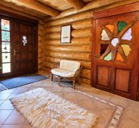 The interior of the cabin features wooden walls, a comfortable chair, and decorative doors.